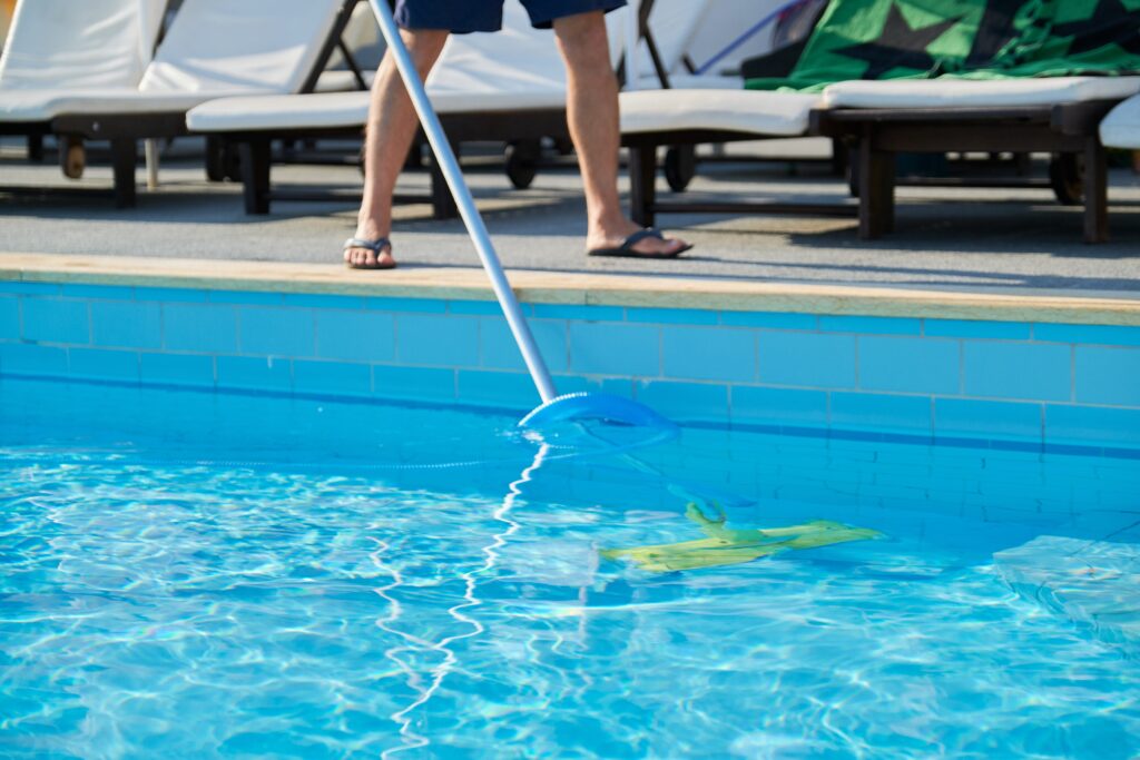 Personne passant l'aspirateur dans une piscine pour réduire le coût d'entretien d'une piscine à long terme