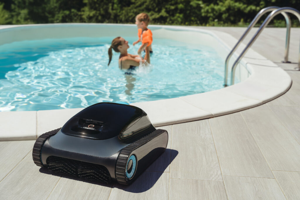 Robot de piscine à chenilles posé au bord du bassin pendant la baignade