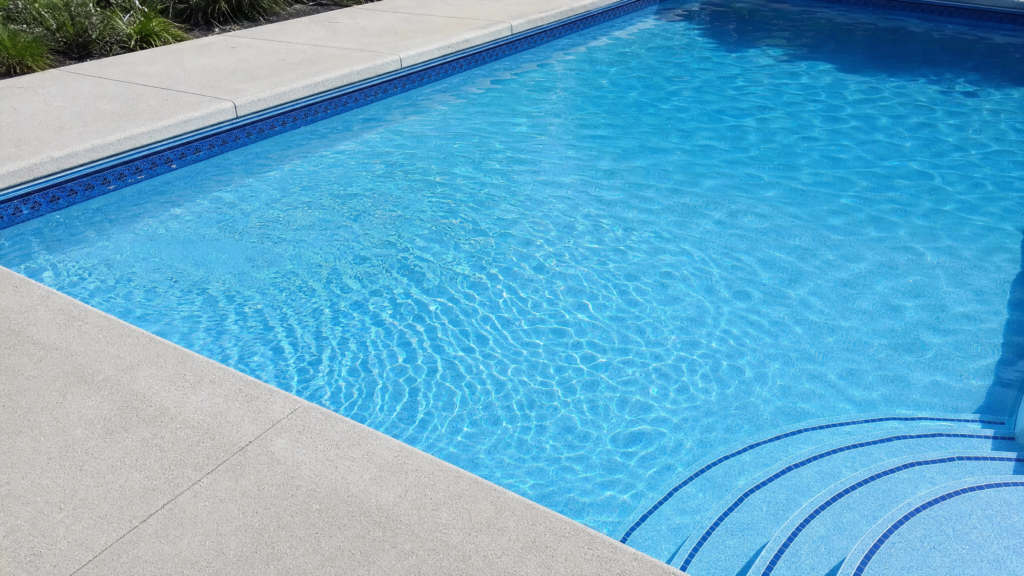 Changer sa toile de piscine creusée : nouvelle toile bleue avec liserés décoratifs et marches d'escalier